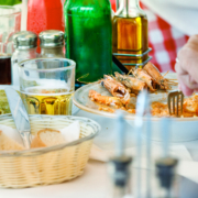 A man hand having lunch with shrimp, green pasta and beer outdoors in Mykonos, Greece.